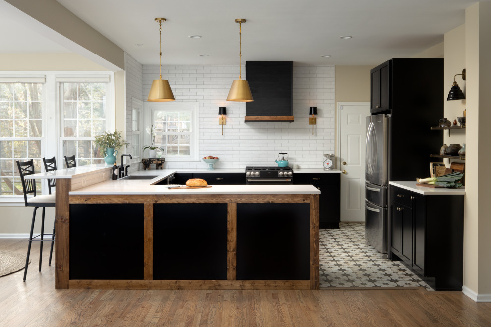 Inspiration for a large country u-shaped open plan kitchen in DC Metro with a drop-in sink, shaker cabinets, black cabinets, quartz benchtops, white splashback, porcelain splashback, black appliances, porcelain floors, a peninsula, multi-coloured floor and white benchtop.