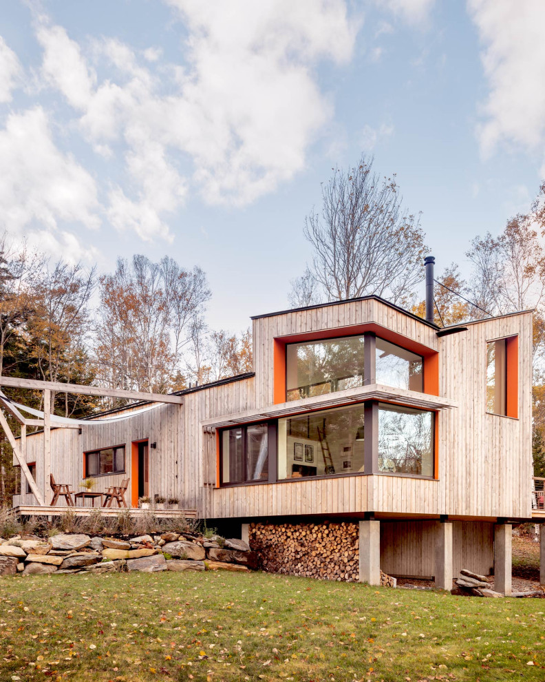 Idée de décoration pour une façade de maison beige design en bois à un étage avec un toit papillon.