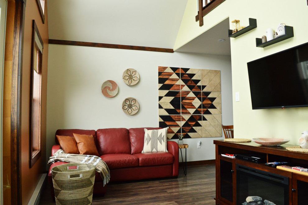 Cette photo montre un petit salon moderne ouvert avec un mur orange, un sol en bois brun, un manteau de cheminée en bois, un téléviseur fixé au mur et un plafond voûté.