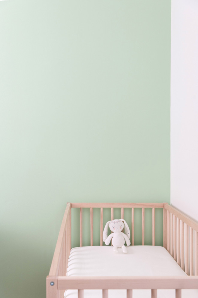 Idée de décoration pour une chambre de bébé neutre design de taille moyenne avec un mur vert et parquet clair.