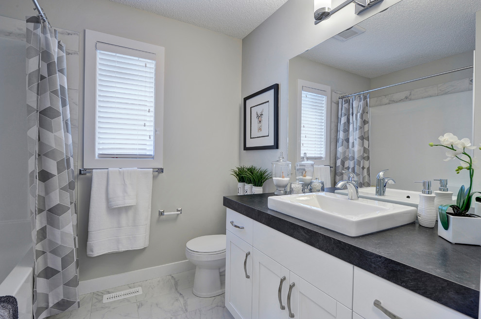 Example of a mid-sized transitional kids' ceramic tile and white floor alcove bathtub design in Edmonton with shaker cabinets, white cabinets, a two-piece toilet, gray walls, a vessel sink and laminate countertops