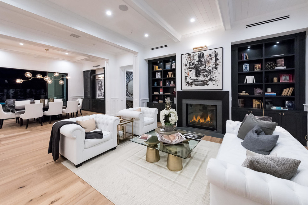 This is an example of a transitional formal open concept living room in Los Angeles with white walls, light hardwood floors, a standard fireplace and beige floor.