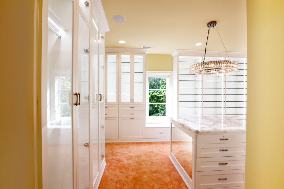 Inspiration for an expansive transitional women's walk-in wardrobe in Chicago with glass-front cabinets, white cabinets and carpet.