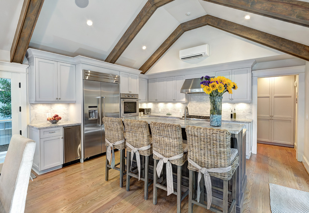 Inspiration for a tropical l-shaped eat-in kitchen in Charleston with shaker cabinets, white cabinets, white splashback, stainless steel appliances, medium hardwood floors and with island.