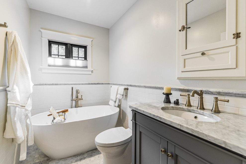 Large elegant master white tile and subway tile marble floor, gray floor and single-sink freestanding bathtub photo in Sacramento with shaker cabinets, gray cabinets, a two-piece toilet, white walls, an undermount sink, quartzite countertops, gray countertops and a built-in vanity