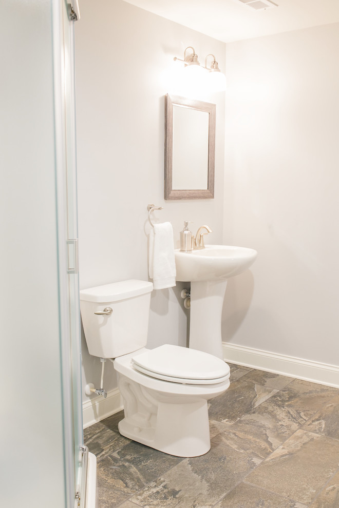 Mid-sized country 3/4 bathroom in Baltimore with a two-piece toilet, grey walls, porcelain floors, a pedestal sink, solid surface benchtops, an alcove shower, white tile and porcelain tile.