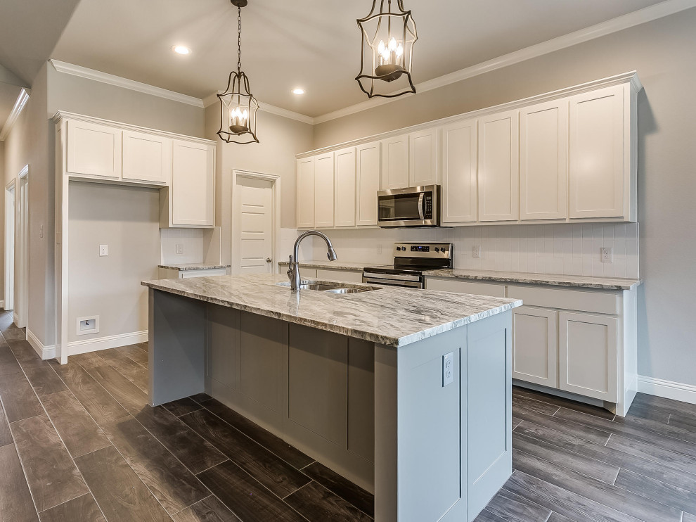 Photo of a mid-sized transitional u-shaped kitchen in Dallas with an undermount sink, shaker cabinets, white cabinets, granite benchtops, white splashback, ceramic splashback, stainless steel appliances, ceramic floors, with island and multi-coloured benchtop.