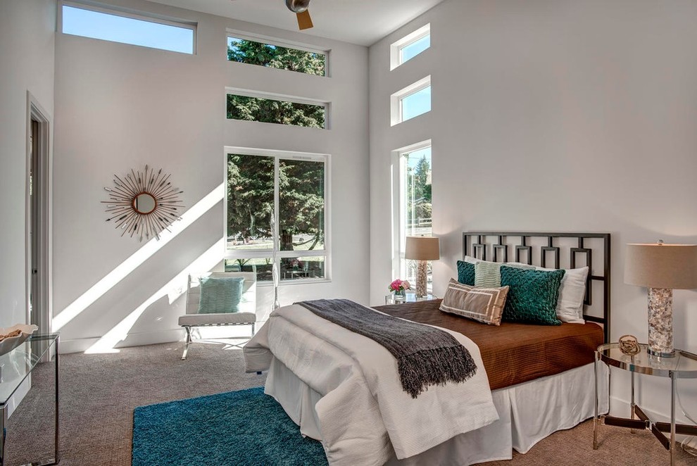 Large transitional master bedroom in Seattle with white walls and carpet.