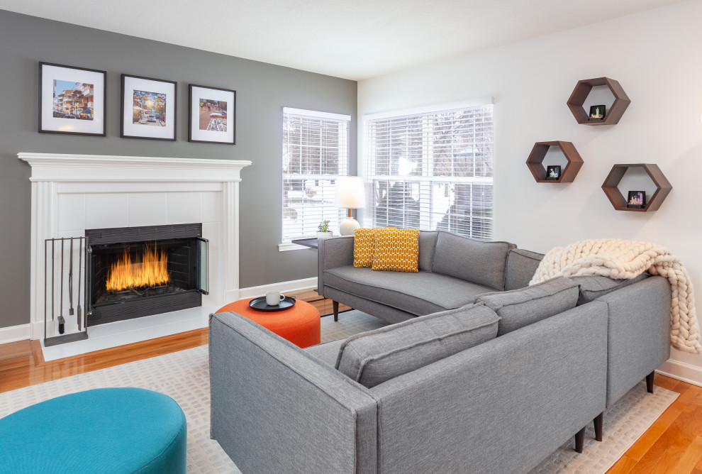 This is an example of a small midcentury open concept family room in Detroit with grey walls, medium hardwood floors, a standard fireplace, a tile fireplace surround, a freestanding tv and brown floor.