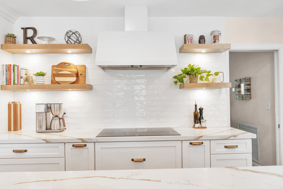 Example of a large transitional medium tone wood floor and brown floor open concept kitchen design in Miami with a farmhouse sink, shaker cabinets, white cabinets, quartz countertops, white backsplash, subway tile backsplash, stainless steel appliances, an island and white countertops