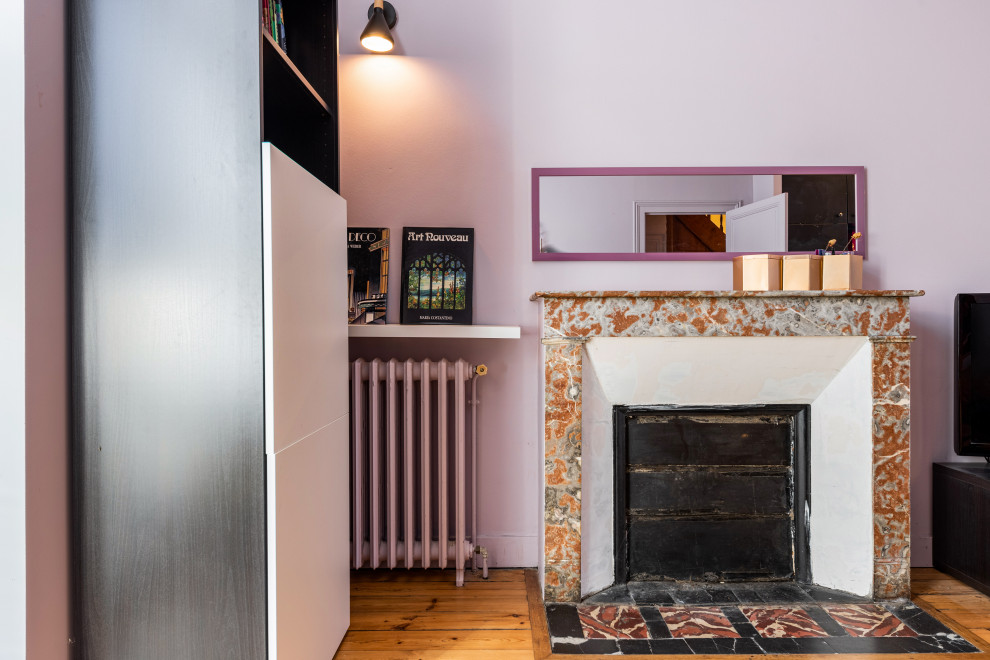 Cette photo montre une salle de séjour chic de taille moyenne avec un mur rose, parquet clair, une cheminée standard et éclairage.