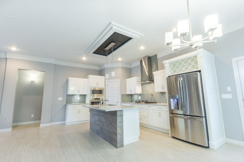 Home design - mid-sized transitional u-shaped ceramic tile home design idea in Austin with a double-bowl sink, flat-panel cabinets, white cabinets, granite countertops, gray backsplash, glass sheet backsplash, stainless steel appliances and an island