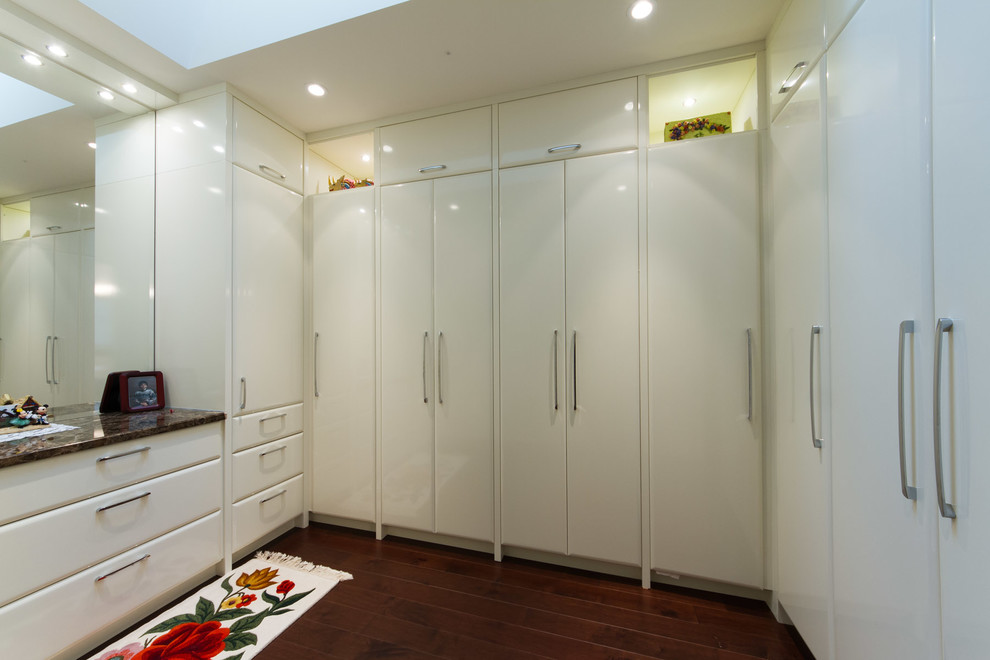 Photo of a mid-sized contemporary gender-neutral walk-in wardrobe in Toronto with flat-panel cabinets, white cabinets and dark hardwood floors.