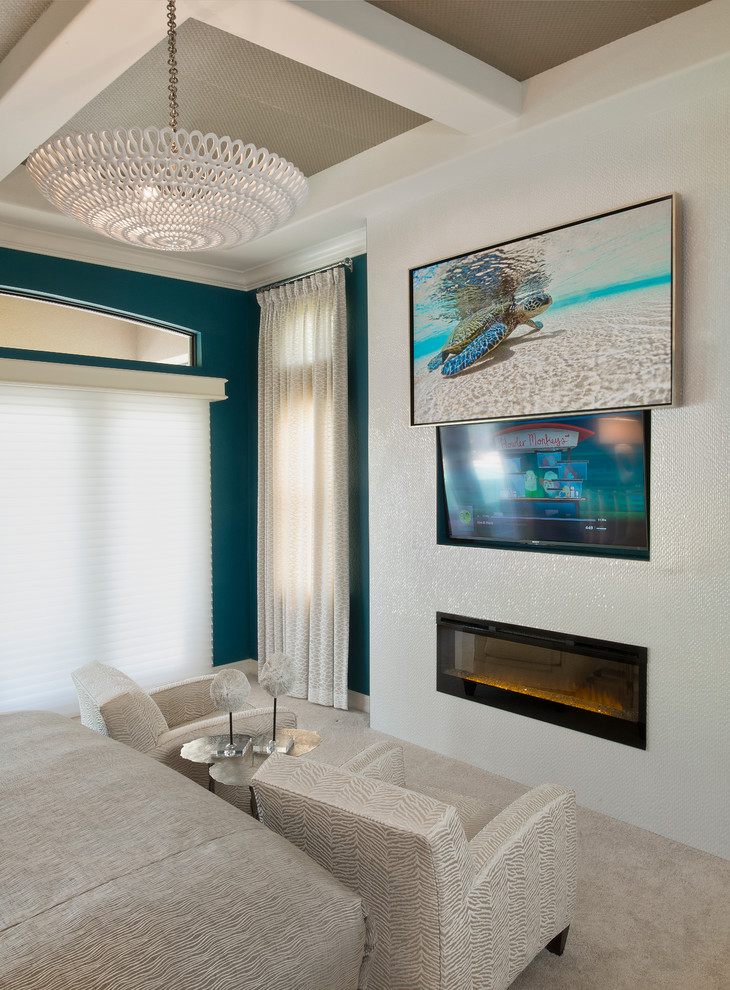 This is an example of a large beach style master bedroom in Miami with blue walls, ceramic floors, a tile fireplace surround, a standard fireplace and grey floor.