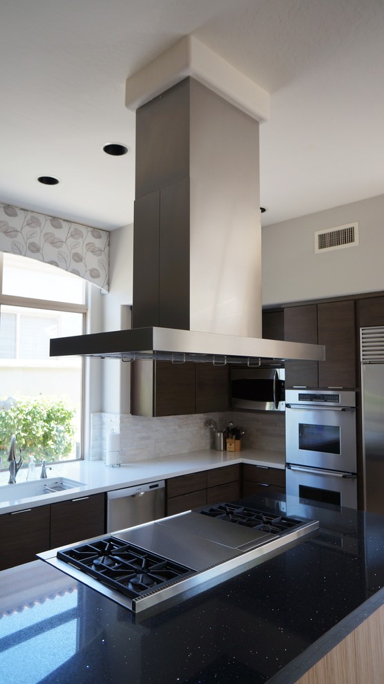 Mid-sized transitional u-shaped travertine floor and beige floor open concept kitchen photo in Phoenix with a single-bowl sink, flat-panel cabinets, dark wood cabinets, quartz countertops, white backsplash, stone tile backsplash, stainless steel appliances and an island