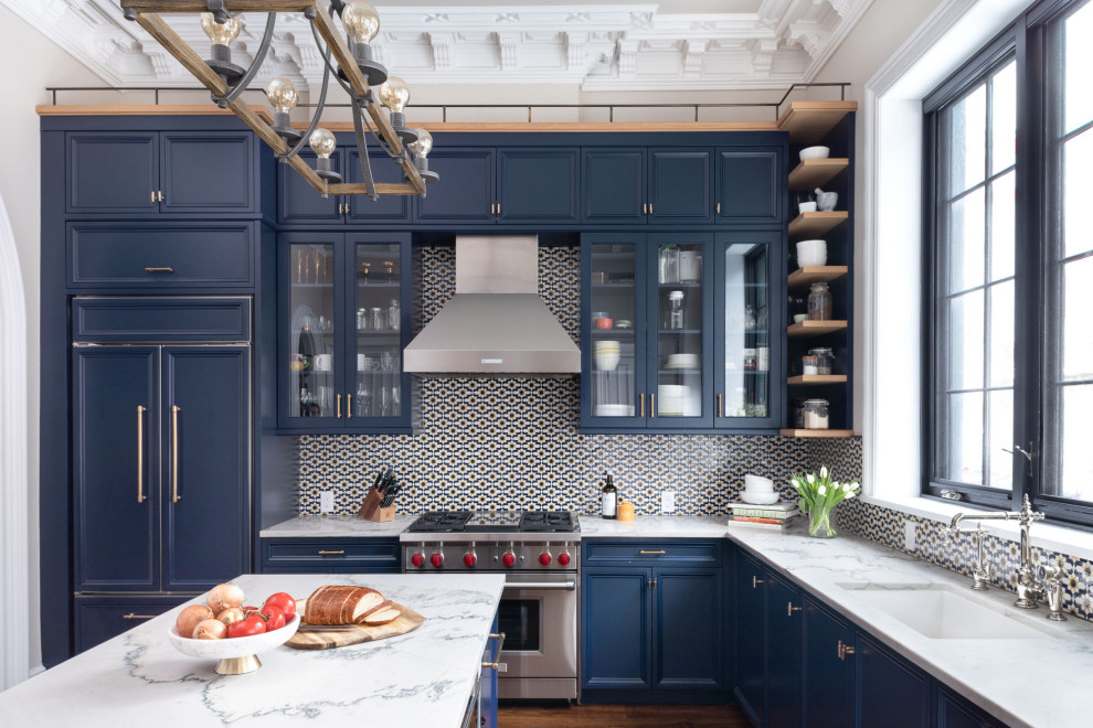 Idéer för ett stort klassiskt vit l-kök, med en undermonterad diskho, luckor med infälld panel, blå skåp, bänkskiva i kvartsit, flerfärgad stänkskydd, stänkskydd i mosaik, integrerade vitvaror, mörkt trägolv, en köksö och brunt golv
