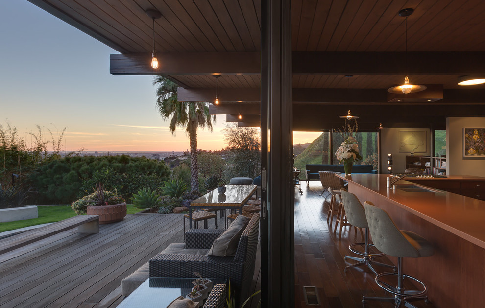 Photo of a large midcentury backyard deck in Los Angeles with an outdoor kitchen and a roof extension.