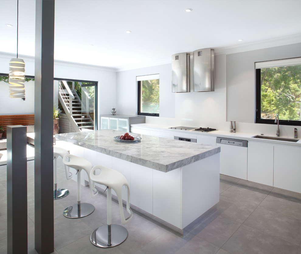 This is an example of a mid-sized contemporary single-wall eat-in kitchen in Sydney with an undermount sink, flat-panel cabinets, white cabinets, granite benchtops, white splashback, glass sheet splashback, stainless steel appliances and with island.