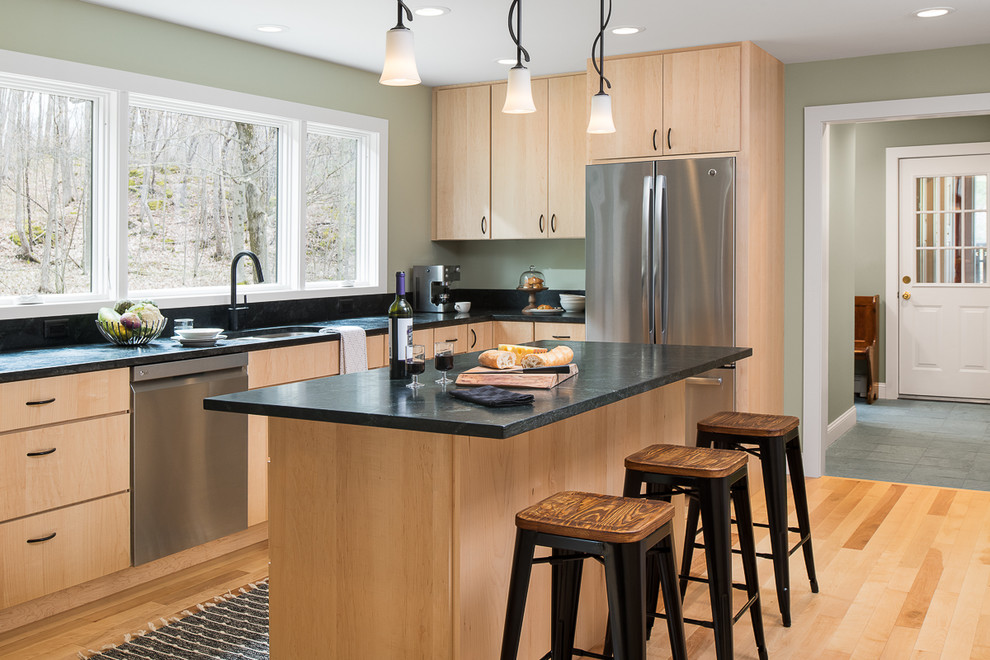 This is an example of a mid-sized transitional l-shaped kitchen in Burlington with an undermount sink, flat-panel cabinets, light wood cabinets, soapstone benchtops, stainless steel appliances, light hardwood floors, with island and green benchtop.