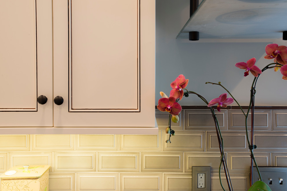Example of a mid-sized transitional u-shaped medium tone wood floor eat-in kitchen design in New York with recessed-panel cabinets, white cabinets, granite countertops, beige backsplash, subway tile backsplash, a peninsula, stainless steel appliances and an undermount sink