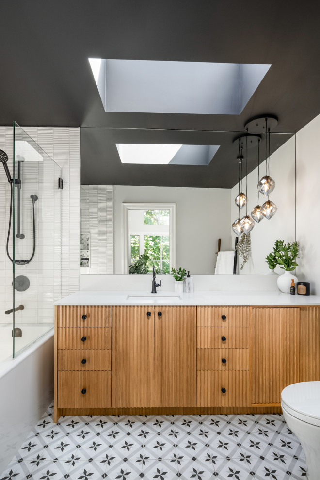 Photo of a mid-sized contemporary master bathroom in Vancouver with medium wood cabinets, an alcove tub, a shower/bathtub combo, a two-piece toilet, white tile, subway tile, white walls, porcelain floors, an undermount sink, engineered quartz benchtops, multi-coloured floor, a hinged shower door, white benchtops, a niche, a single vanity, a built-in vanity and flat-panel cabinets.