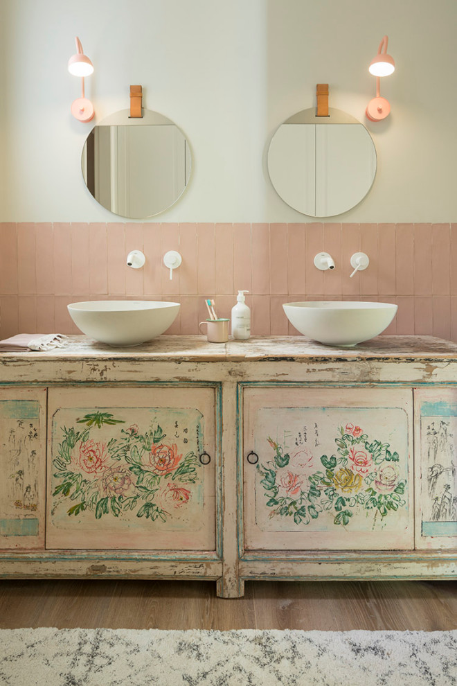 Photo of a mid-sized traditional kids bathroom in Barcelona with medium hardwood floors, a vessel sink, wood benchtops, distressed cabinets, pink tile, beige walls and flat-panel cabinets.