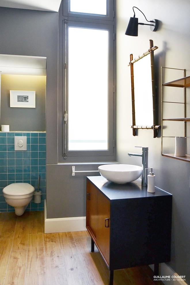 Midcentury bathroom in Lyon with a curbless shower, blue tile, ceramic tile, grey walls, light hardwood floors and stainless steel benchtops.