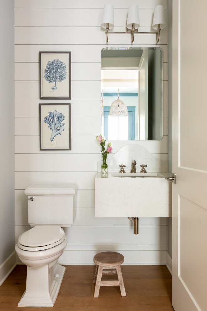 Réalisation d'un WC et toilettes marin avec un placard à porte plane, des portes de placard blanches, WC séparés, un mur gris, un sol en bois brun, un lavabo encastré, un sol marron, un plan de toilette blanc, meuble-lavabo suspendu et du lambris de bois.