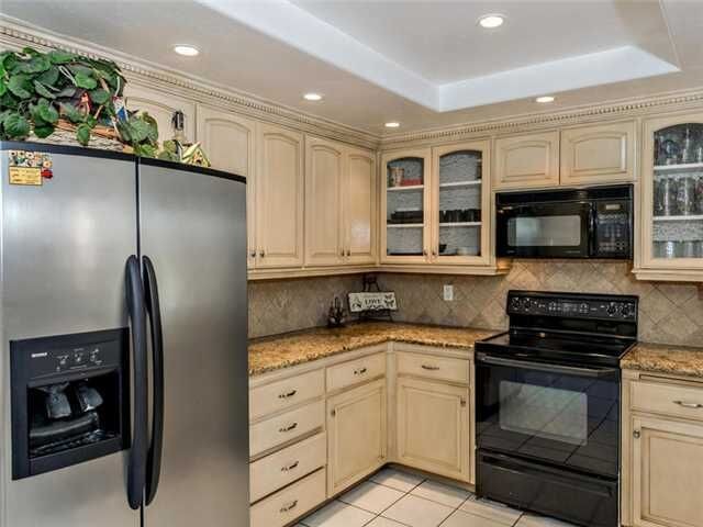 Example of a large transitional u-shaped ceramic tile open concept kitchen design in Denver with an undermount sink, raised-panel cabinets, beige cabinets, granite countertops, beige backsplash, terra-cotta backsplash and black appliances