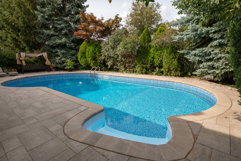 Photo of a medium sized modern back kidney-shaped swimming pool in Toronto with with pool landscaping and concrete paving.