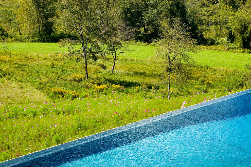 Mid-sized country backyard rectangular infinity pool in Bridgeport with natural stone pavers.