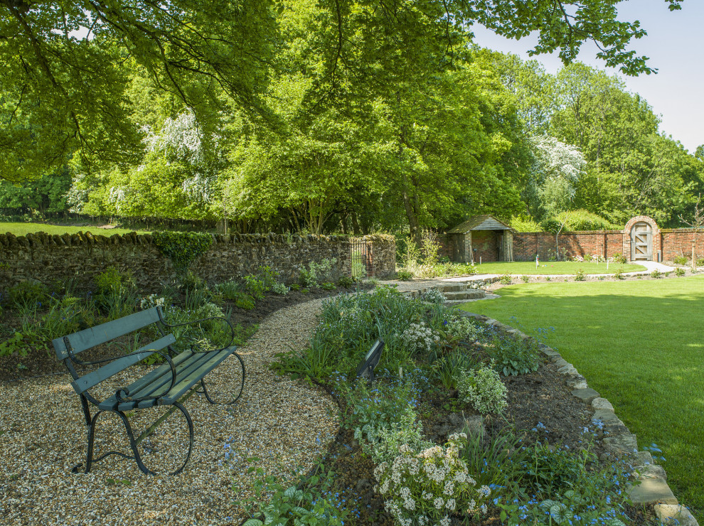Geometrischer Klassischer Garten hinter dem Haus mit Hochbeet, Natursteinplatten und Steinzaun in Sussex