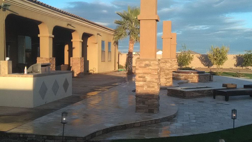 Photo of a large back patio in Phoenix with an outdoor kitchen and natural stone paving.