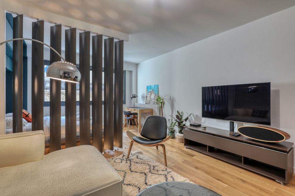 Bild på ett mellanstort funkis allrum med öppen planlösning, med en hemmabar, grå väggar, ljust trägolv, en fristående TV och brunt golv