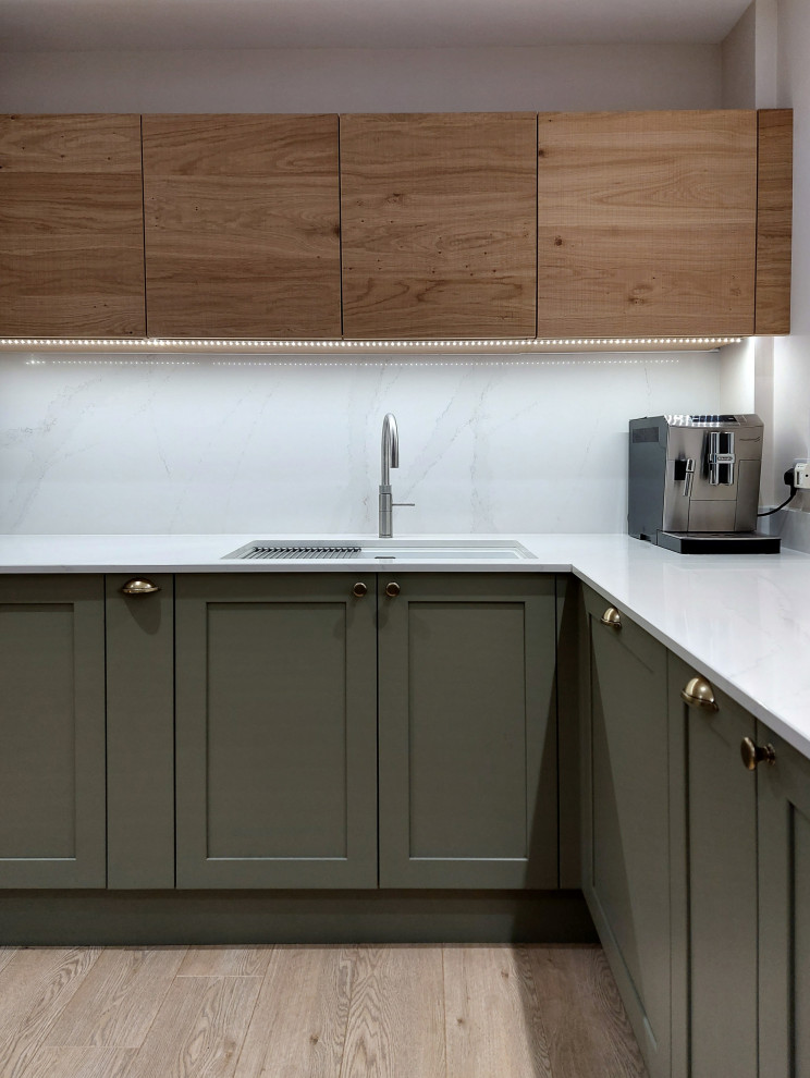Photo of a medium sized traditional u-shaped open plan kitchen in Other with a double-bowl sink, shaker cabinets, green cabinets, quartz worktops, white splashback, engineered quartz splashback, stainless steel appliances, plywood flooring, a breakfast bar, beige floors and white worktops.