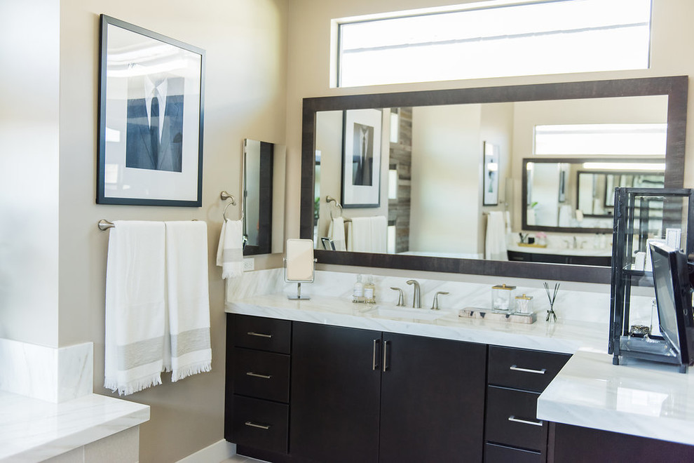 This is an example of a mid-sized traditional master bathroom in Las Vegas with flat-panel cabinets, dark wood cabinets, beige tile, porcelain tile, beige walls, porcelain floors, a drop-in sink and marble benchtops.
