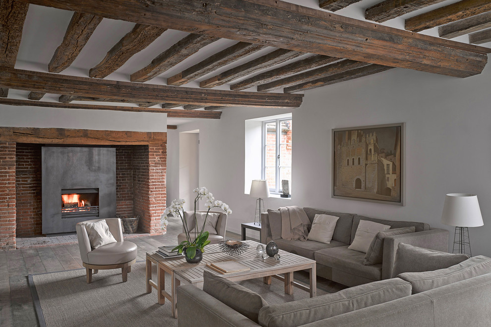 This is an example of a country living room in London with white walls, a standard fireplace and brown floor.