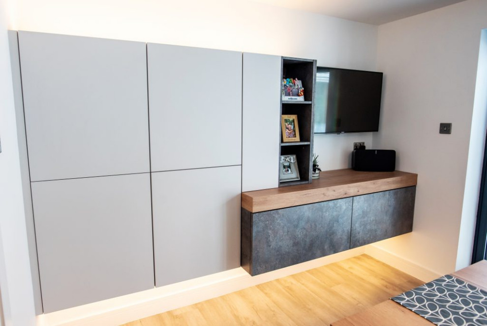Large modern grey and white enclosed kitchen with grey cabinets, concrete worktops, white splashback, an island, grey worktops and feature lighting.