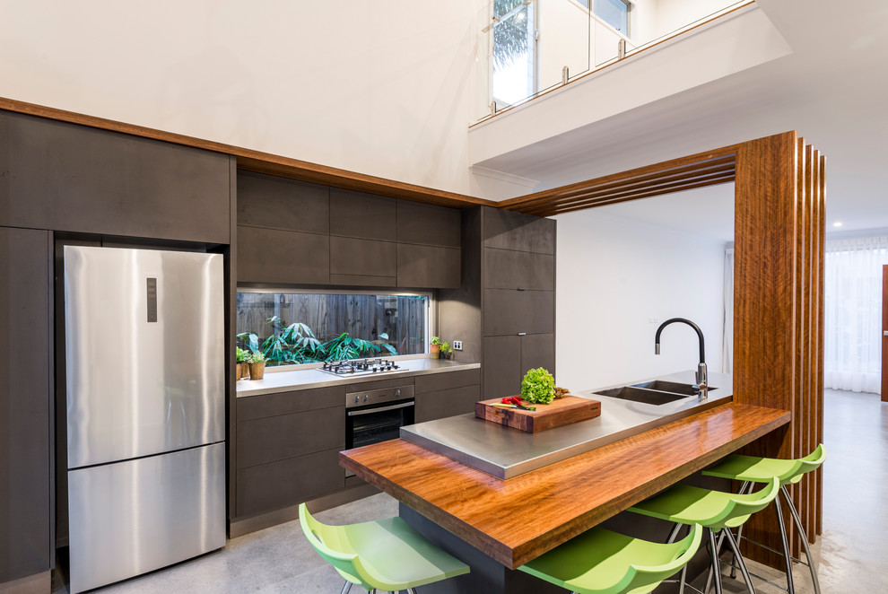 Small modern galley open plan kitchen in Brisbane with flat-panel cabinets, grey cabinets, stainless steel benchtops, glass sheet splashback, stainless steel appliances, concrete floors, with island and grey floor.