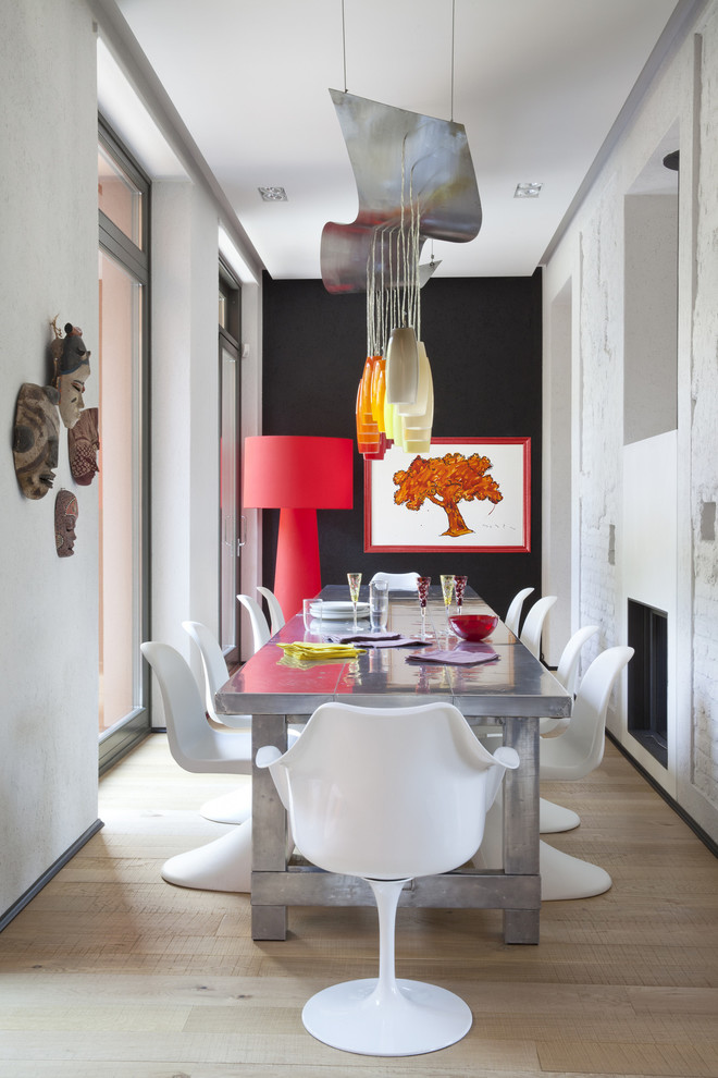 Design ideas for a small eclectic dining room in Milan with white walls and light hardwood floors.