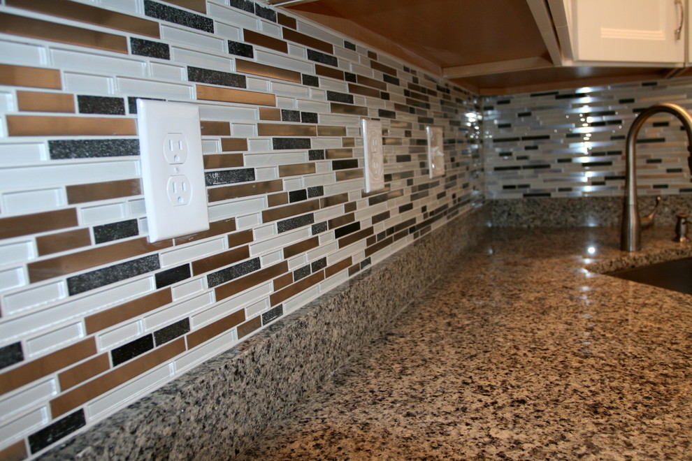 Inspiration for a mid-sized modern medium tone wood floor kitchen remodel in Baltimore with an undermount sink, white cabinets, granite countertops, multicolored backsplash, glass tile backsplash and stainless steel appliances