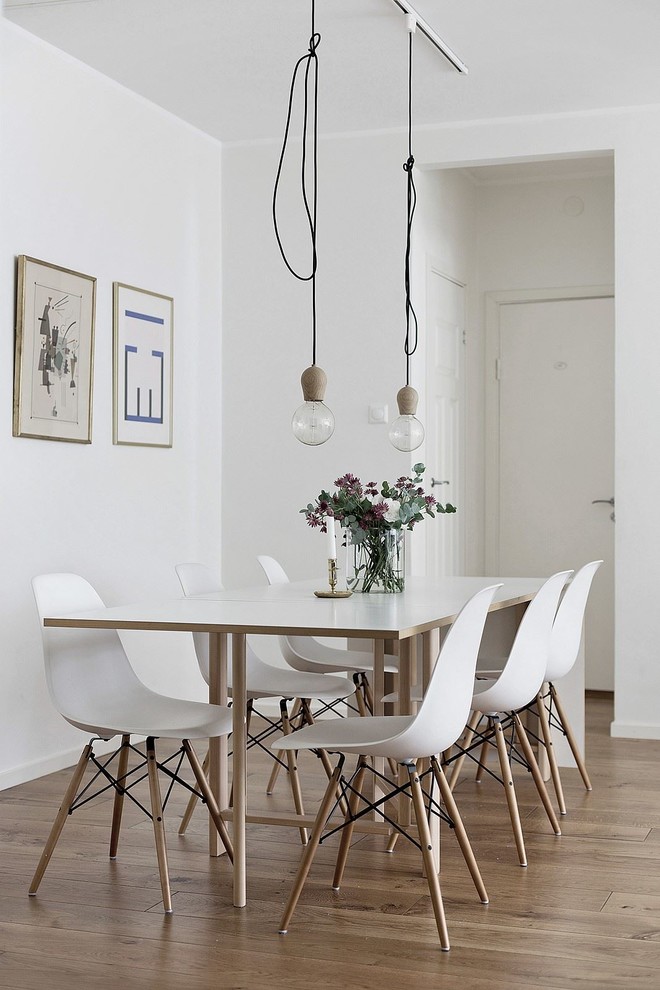 Inspiration for a mid-sized scandinavian dining room in Stockholm with white walls, medium hardwood floors and brown floor.
