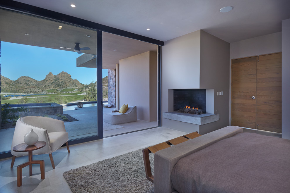 This is an example of a large master bedroom in Other with beige walls, porcelain floors, a corner fireplace, a concrete fireplace surround and grey floor.