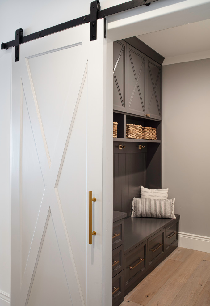 Mid-sized traditional single-wall utility room in San Francisco with shaker cabinets, grey cabinets, wood benchtops, grey splashback, timber splashback, grey walls, light hardwood floors, a concealed washer and dryer, grey floor and grey benchtop.