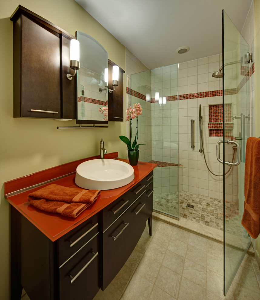 Design ideas for a small transitional 3/4 bathroom in Atlanta with a vessel sink, furniture-like cabinets, dark wood cabinets, glass benchtops, an alcove shower, a two-piece toilet, beige tile, ceramic tile, beige walls and ceramic floors.