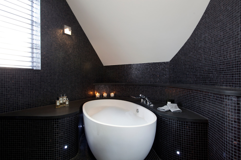This is an example of a large contemporary master bathroom in London with gray tile, a freestanding tub, mosaic tile, mosaic tile floors, an undermount sink, a corner shower, a one-piece toilet and white walls.