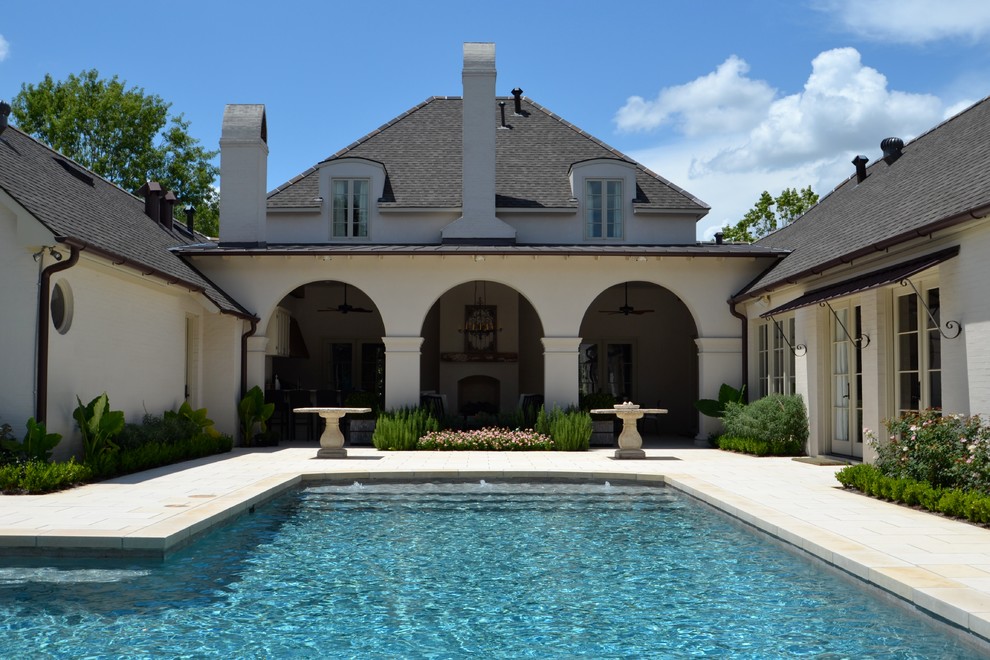 Design ideas for a mid-sized traditional backyard custom-shaped lap pool in New Orleans with a hot tub and natural stone pavers.