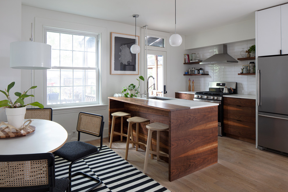 Small contemporary single-wall eat-in kitchen in Richmond with flat-panel cabinets, dark wood cabinets, white splashback, stainless steel appliances, with island and white benchtop.