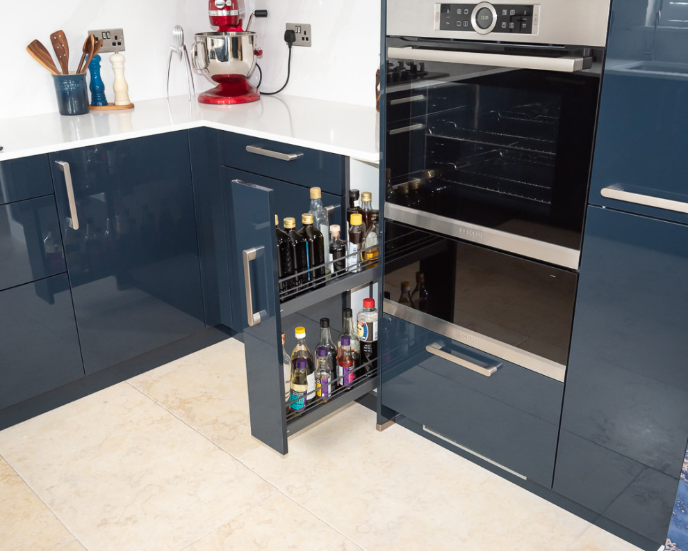 Photo of a mid-sized contemporary u-shaped eat-in kitchen in Berkshire with flat-panel cabinets, blue cabinets, quartzite benchtops, black appliances, no island and white benchtop.