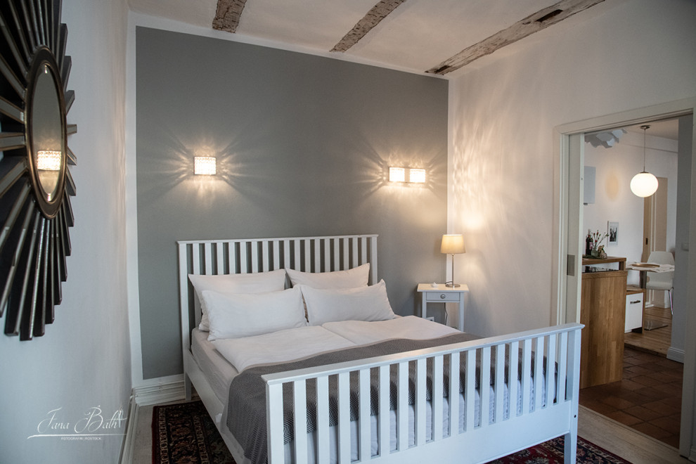 Kleines Nordisches Schlafzimmer mit grauer Wandfarbe, Laminat, weißem Boden und freigelegten Dachbalken in Sonstige